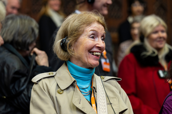 a woman with headphones on smiles with people in the background