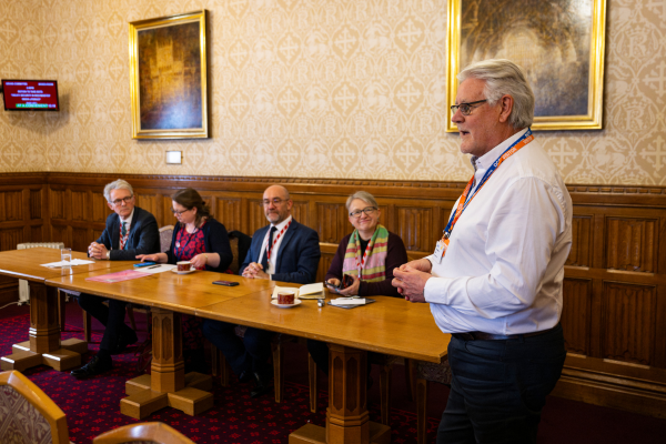 A man stands next to  a seated panel of Lords 