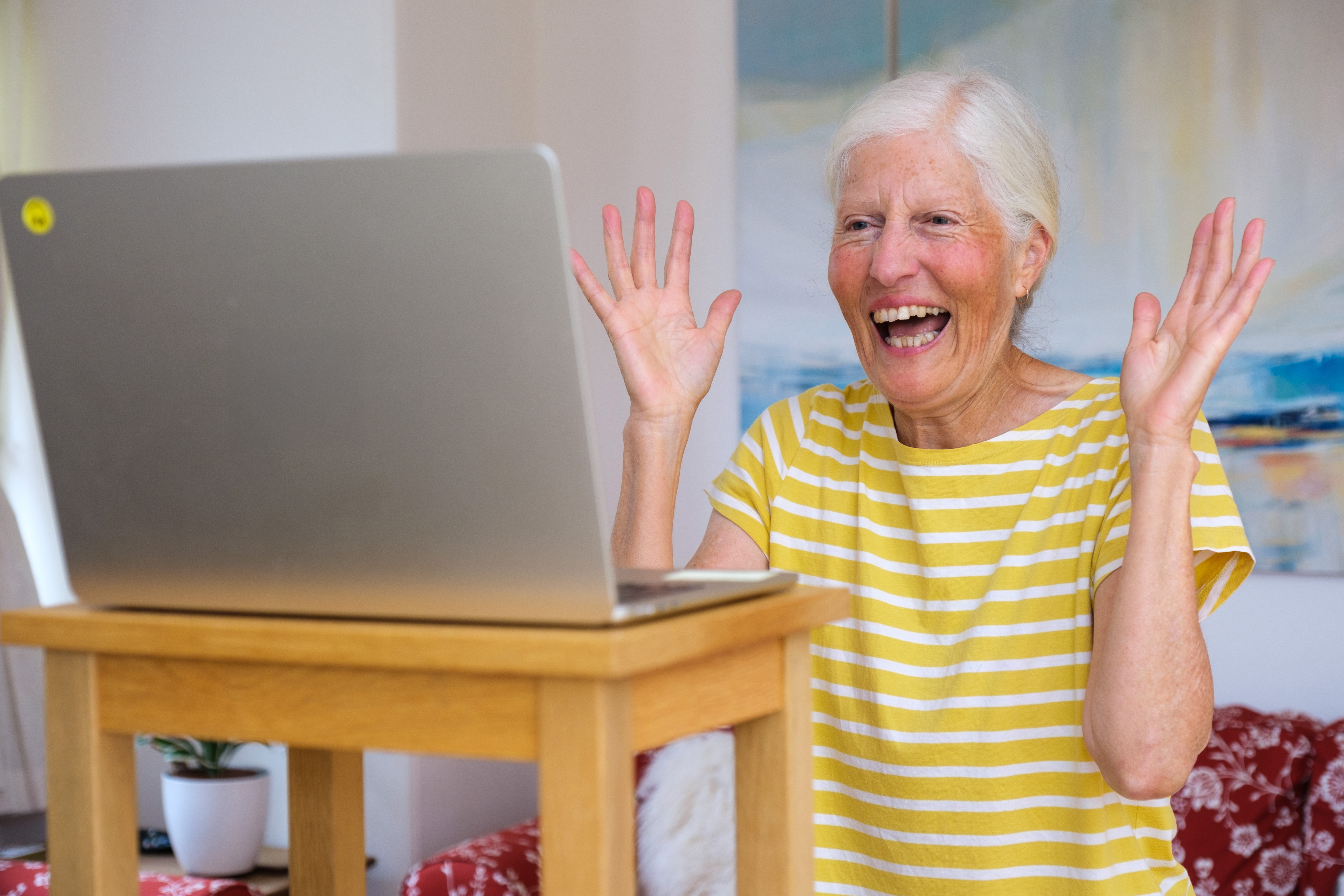 A woman smiles at an open laptop.