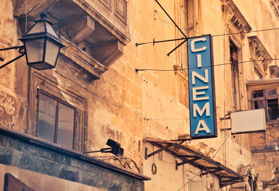 building with a blue sign coming off it saying 'cinema'