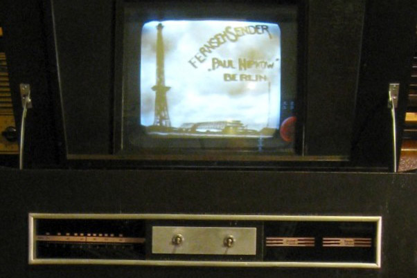 a 1930s looking small tv screen with gold controls below