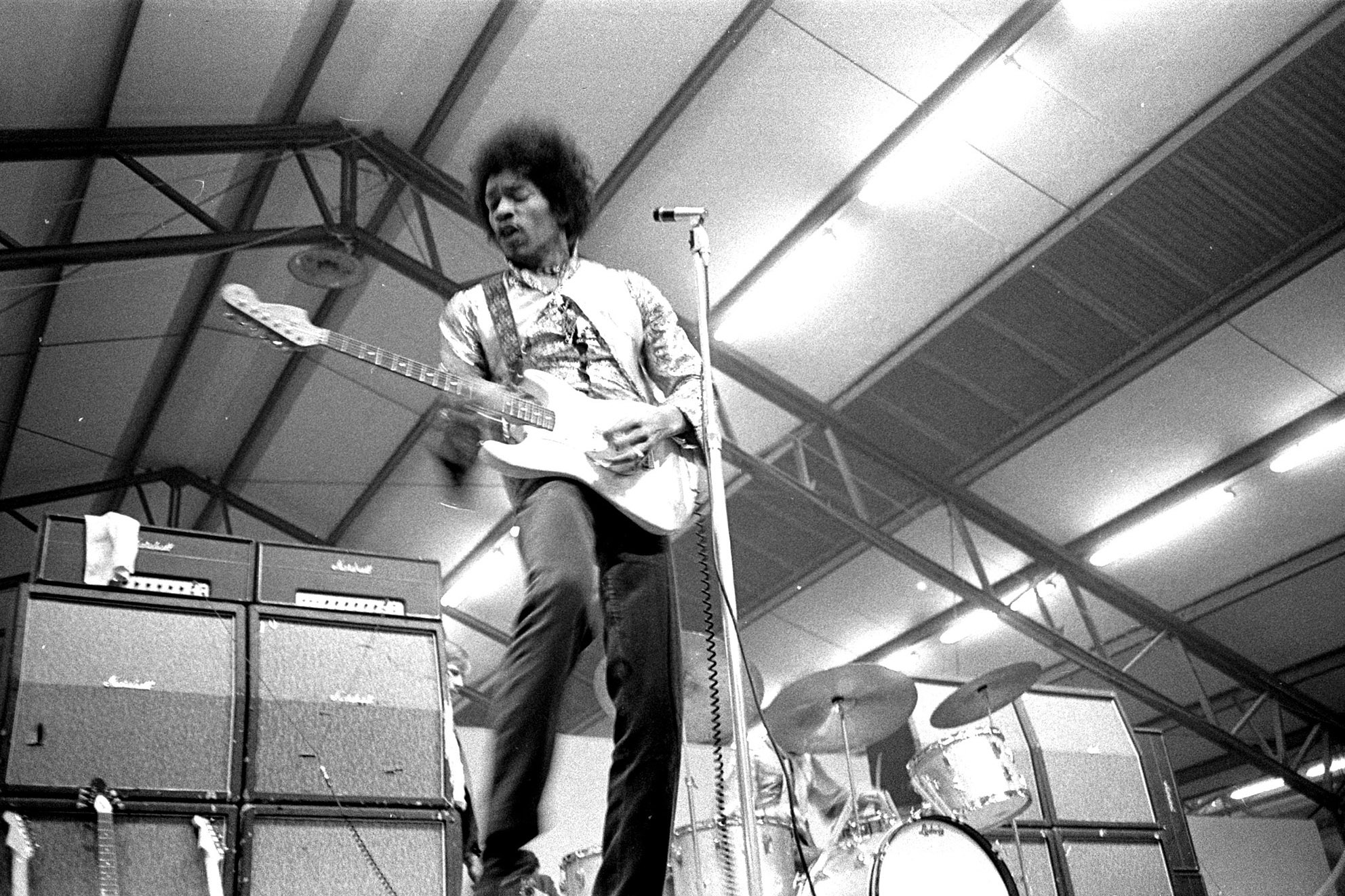 a black and white photo of jimi hendrix playing guitar on stage 
