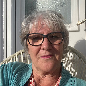 A woman smiling - she is sitting outside