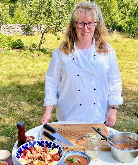a woman with dark blonde curly hair and glasses smiling