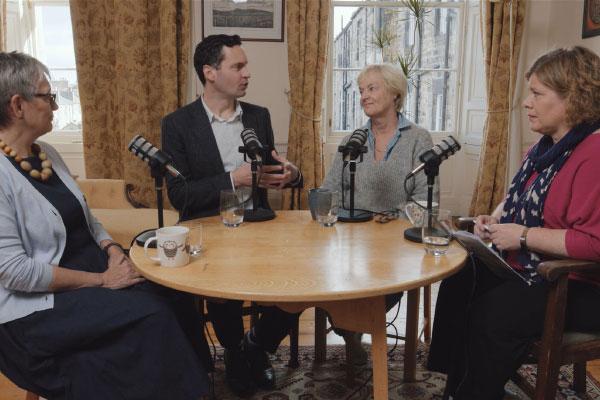 Four people sitting around a table inside a home, havinga discussion