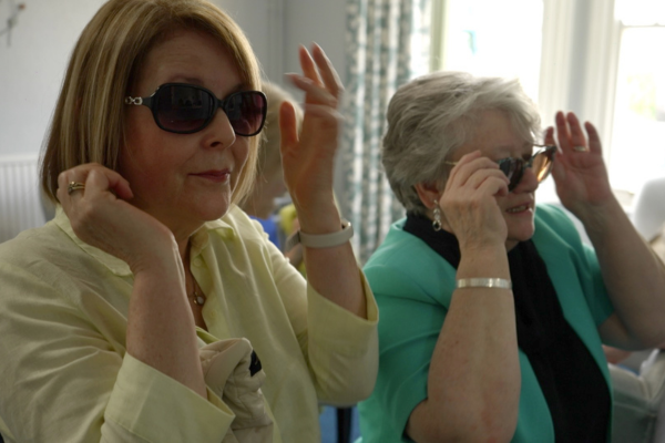 Two women try on sunglasses in a mirror