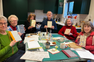 Six people sat round a table holding patterned notebooks