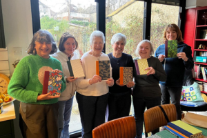 <p>u3a members holding their homemade notebooks</p>