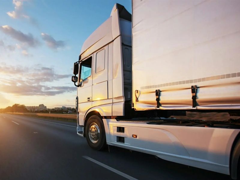 lorry driving on road towards sunrise