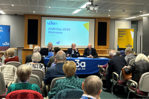 A crowded room with three people sat at the head table.