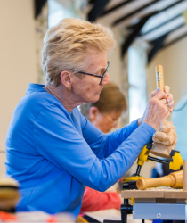 Woman in a blue top using woodcarving tools