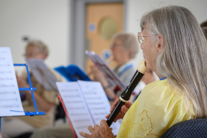 women playing recorder reading sheet music in a group