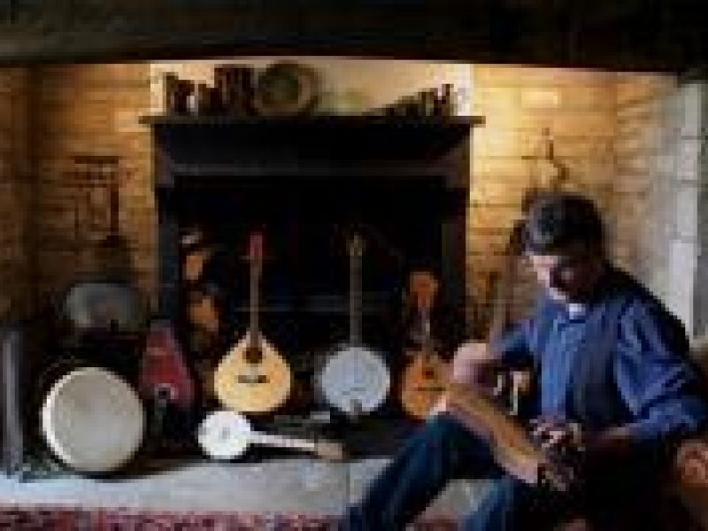 Man with stringed instruments in front of fireplace
