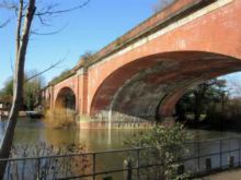a river flowing under the arch of a red bridge