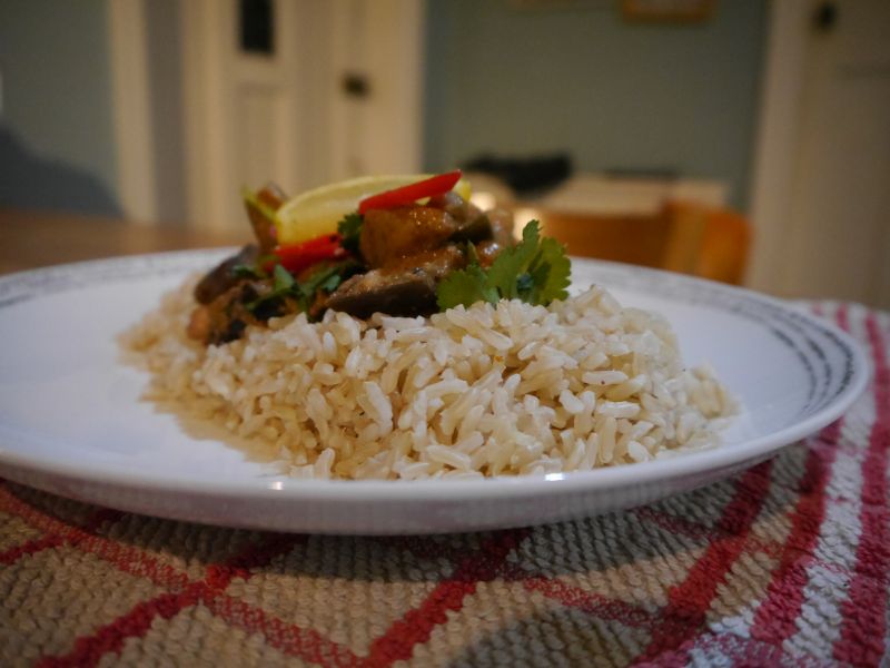 Photo of aubergine curry and rice, garnished with lemon, chillis and coriander