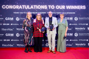 four people pose on a red carpet with two awards