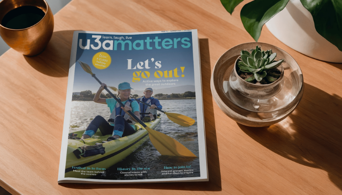 u3a matters magazine on a wooden table surrounded by plants