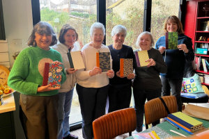 Six women holding up homemade notebooks