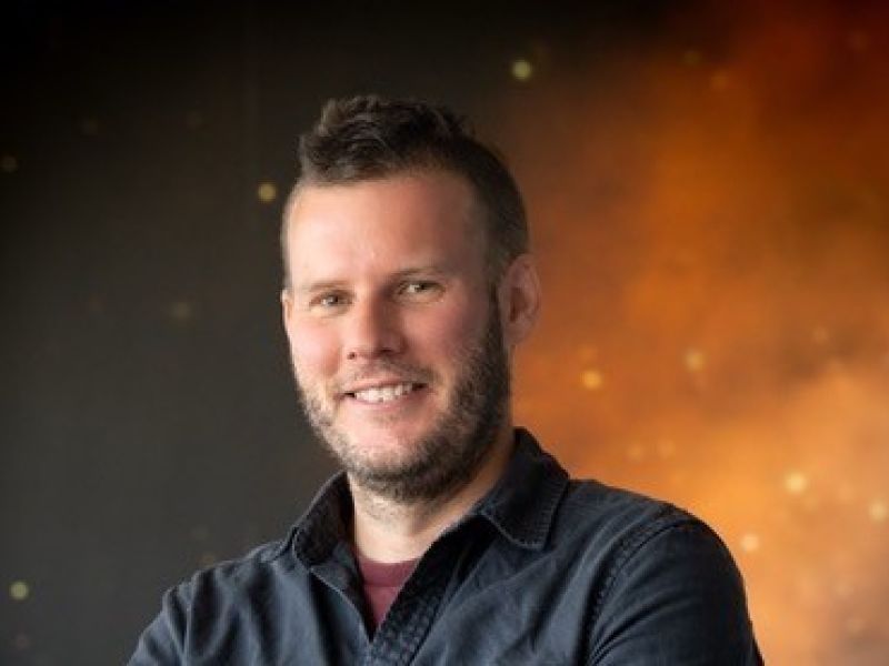 professor stephen wilkins smiling at the camera with starry space backgroundith brain highlighted pink