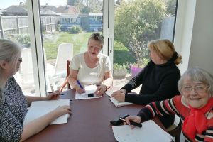 Four women sitting around a table writing in notebooks