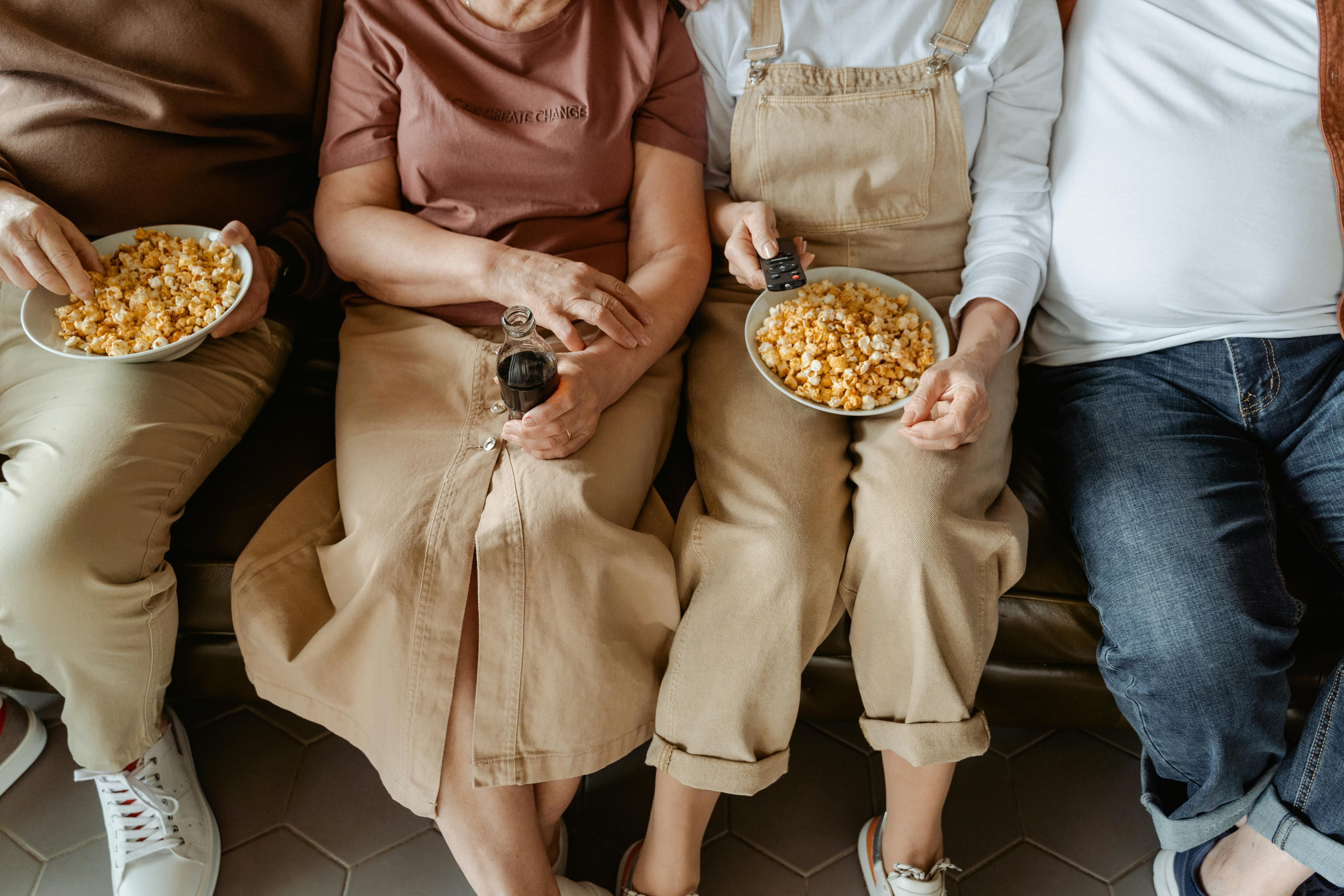 Photo of four people watching TV with snacks