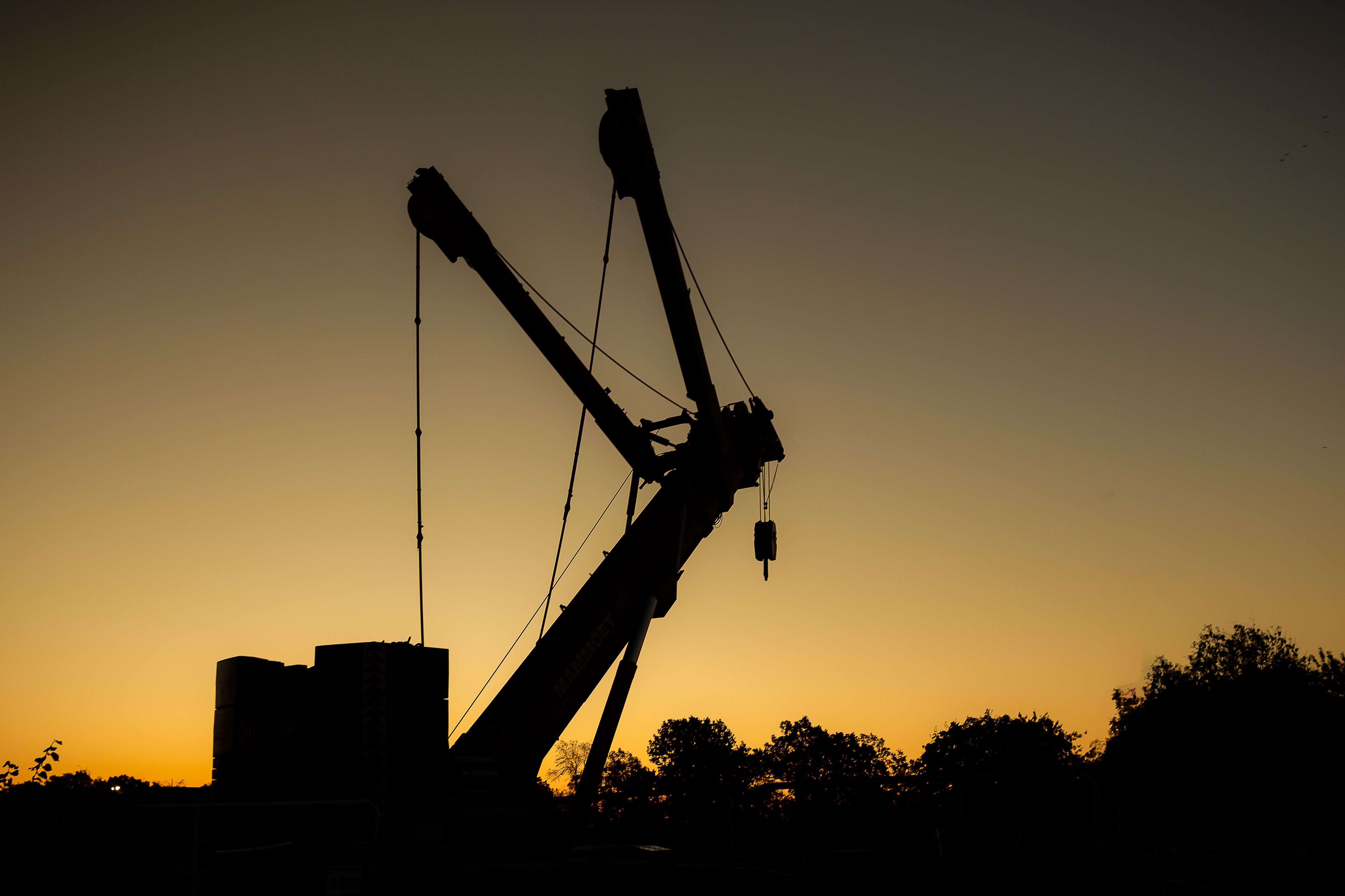 crane in foreground silhouetted against sunrise