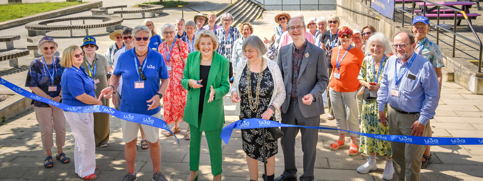 A group of people at u3a Festival 26, including Diana Moran, cutting the ribbon to officially open the Festival
