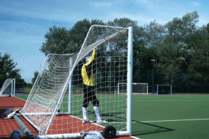 man in football gear standing in goal with his arms raised