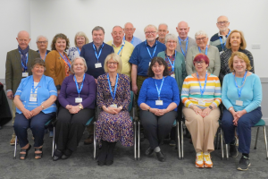 20 u3a council members pose for a photo in front of a white wall